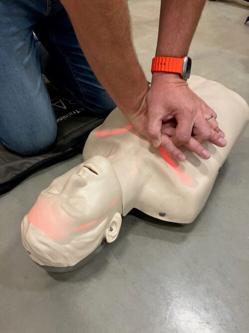 Participant of training course performing CPR on a Brayden mannequin, showing how the brain lights up when it is done correctly.