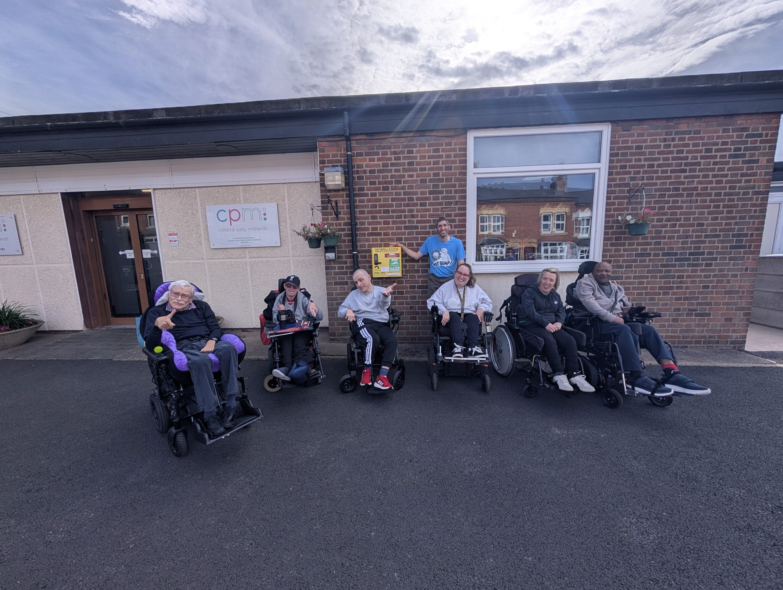 Citizens from Cerebral Palsy Midlands outside the Harborne centre with the new combined emergency medical cabinet with defib and bleed kit.